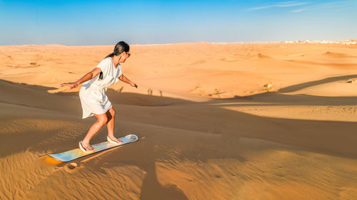 Full length of woman walking on sand at beach