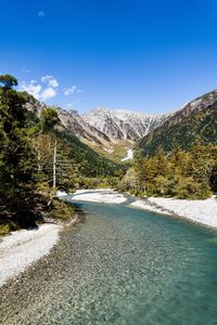 Scenic view of snowcapped mountains against blue sky