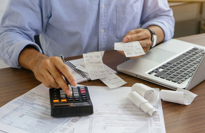 Midsection of man using mobile phone while sitting on table