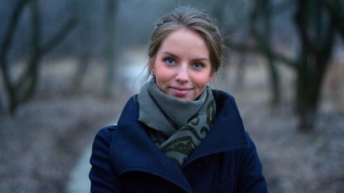 Portrait of smiling young woman in forest during winter