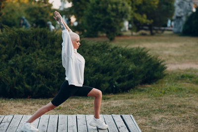 Woman sitting on bench against plants