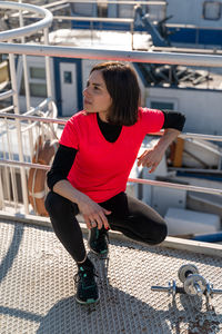 Cute young woman taking a break from exercises with dumbbells on a boat - health wellness concept