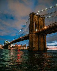 View of suspension bridge over river at night