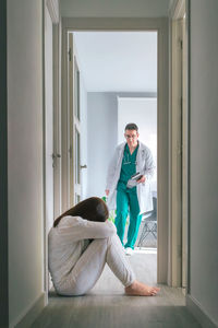 Worried physician running to help mental disorder patient sitting on floor in mental health center