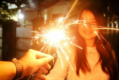 Close-up of woman holding sparkler at night