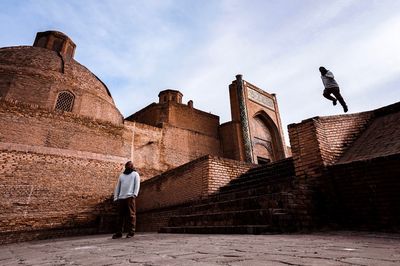 Rear view of man standing on wall against sky