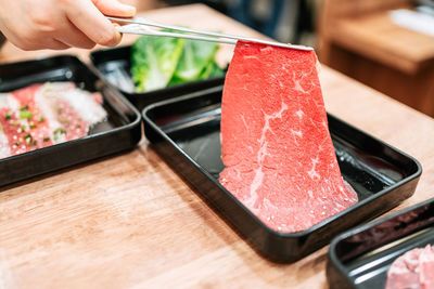 Hand picks a premium rare slices of kagoshima wagyu a5 beef with marbled texture.