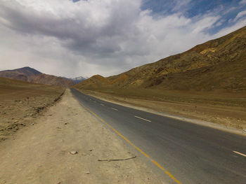 Road leading towards mountains against sky