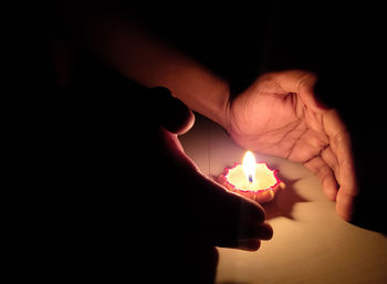 Cropped hands of person by diya on floor at home