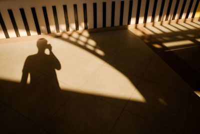 Shadow of man walking on tiled floor