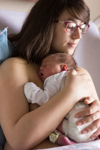 Mother with eyeglasses holding newborn baby