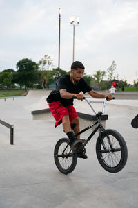 Man riding bicycle on street against sky