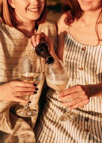 Happy smiling people holding glasses drink wine on the beach at sunset