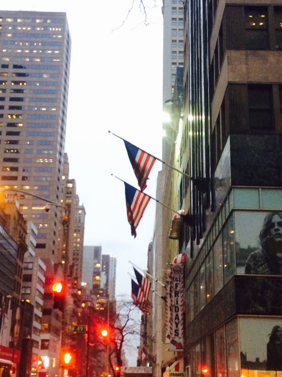 building exterior, architecture, built structure, city, flag, skyscraper, low angle view, national flag, patriotism, identity, american flag, office building, tall - high, city life, modern, tower, building, clear sky, sky, outdoors