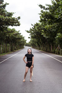 Full length portrait of young woman on road