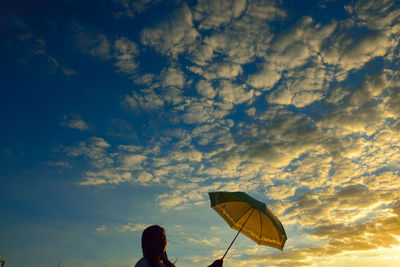 Woman holding umbrella against cloudy sky