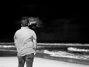 Rear view of man standing in front of sea