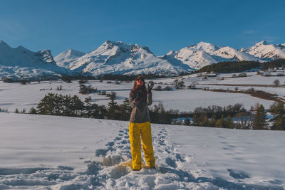 A full-body shot of a young caucasian woman playing with snow in the french alps mountains
