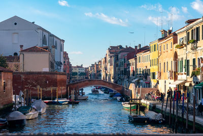 Bridge over canal amidst buildings in city against sky