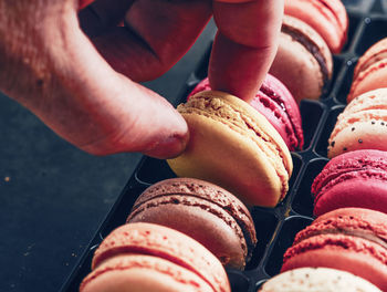 Cropped hand holding colorful macaroon on table