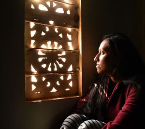Portrait of woman looking away while standing in dark room