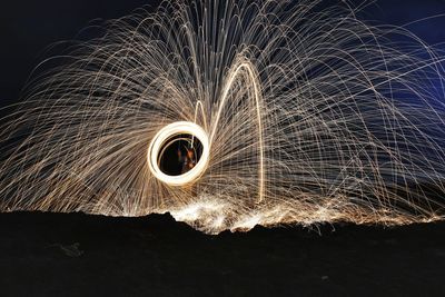 Person spinning wire wool in forest during night