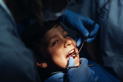 Dentist operating cheerful boy in medical clinic