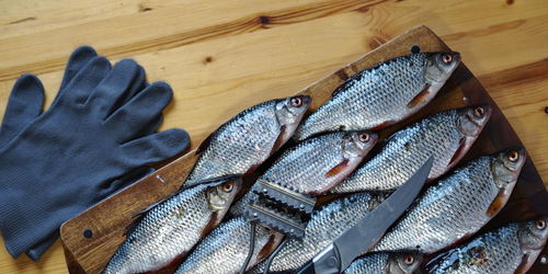 Raw freshwater fish crucian carp on a kitchen cutting board with knives prepared for cleaning.