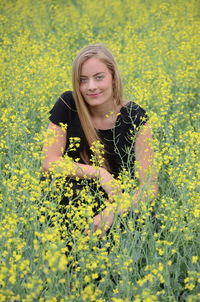 Portrait of woman with yellow flowers in field