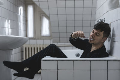 Young man sitting against wall