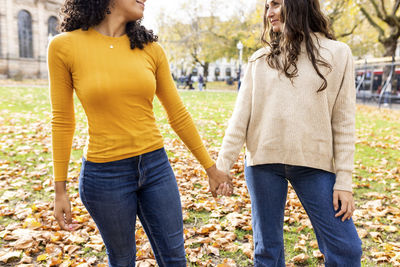 Woman holding hand of friend at autumn park