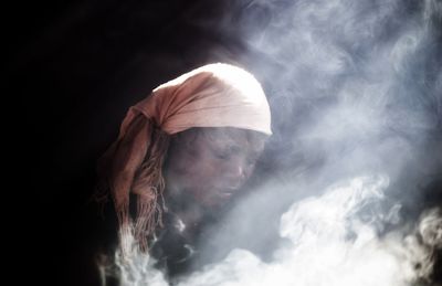 Digital composite image of woman amidst smoke against black background