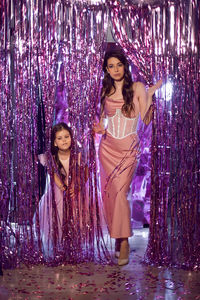 Portrait of a beautiful woman and a daughter in a pink dress, corset and shoes for christmas