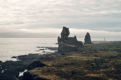 Rock formation on beach against sky