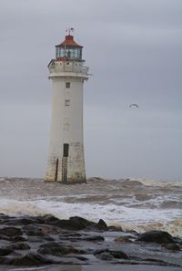 Lighthouse by sea against sky