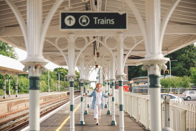 Full length of woman amidst poles at railroad station platform