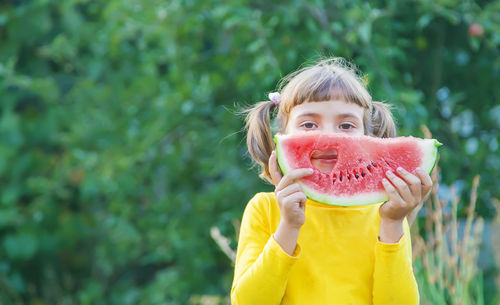 Cute girl with slice of watermelon standing outdoors