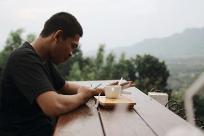 Midsection of man with coffee cup sitting on table