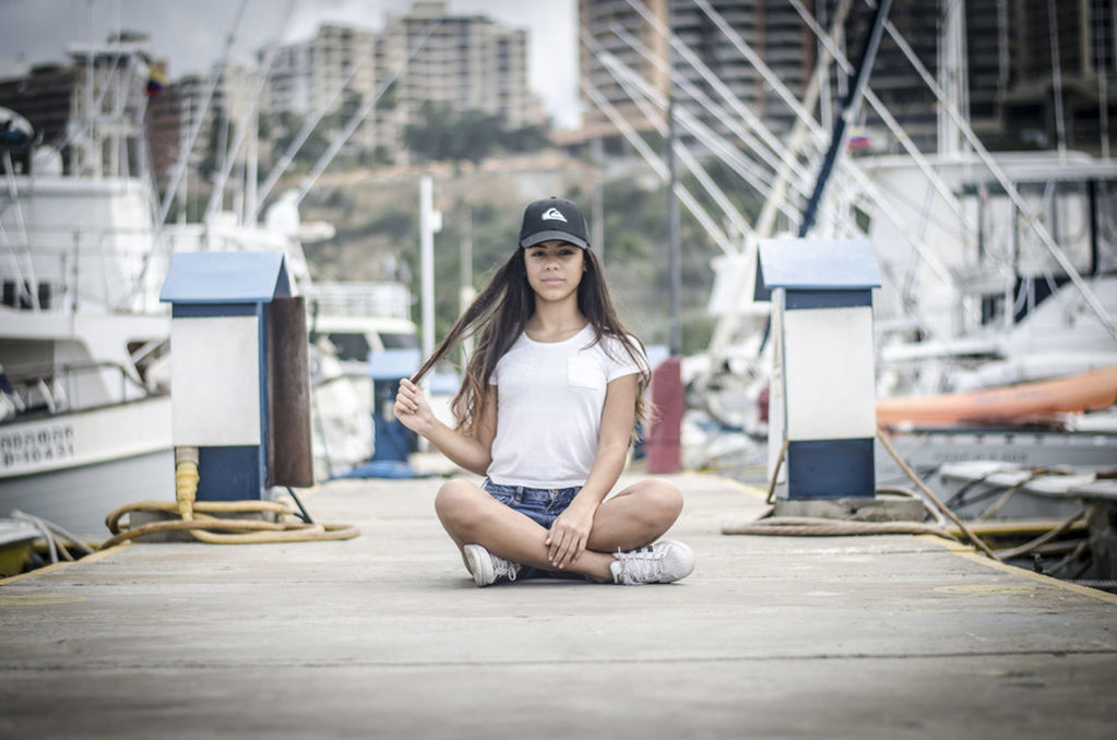 FULL LENGTH OF YOUNG WOMAN USING WHILE SITTING ON CAMERA