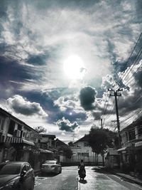 Cars on road against cloudy sky