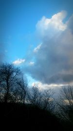 Low angle view of bare trees against cloudy sky