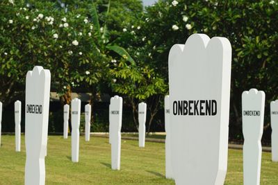 Text on white cemetery against trees