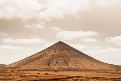 Scenic view of desert against cloudy sky