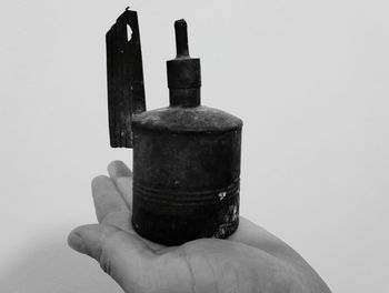 Close-up of hand holding metal against white background