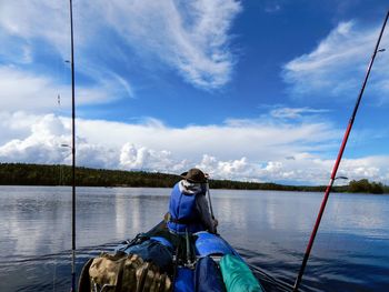 Rear view of man sitting on boat against sky