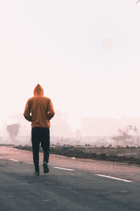 Rear view of man standing on road against sky