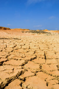 Landscape with dry cracked soil and blue sky.