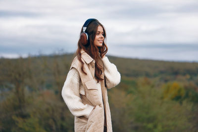 Portrait of young woman standing against trees