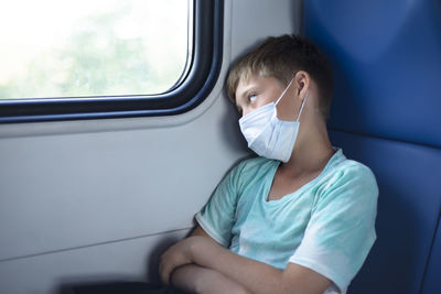 A boy in a medical protective mask rides a train. dreaming. i thought about it.