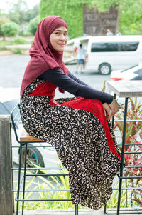 Side view portrait of woman wearing hijab sitting on chair
